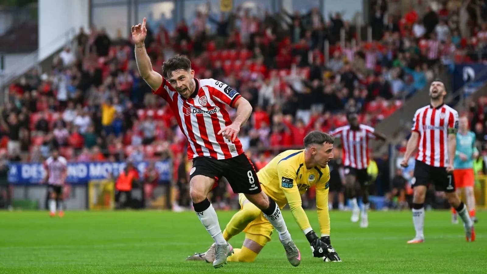Jugador celebrando gol en partido con afición al fondo