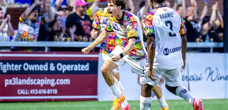 Jugador celebra un gol con aficionados detrás