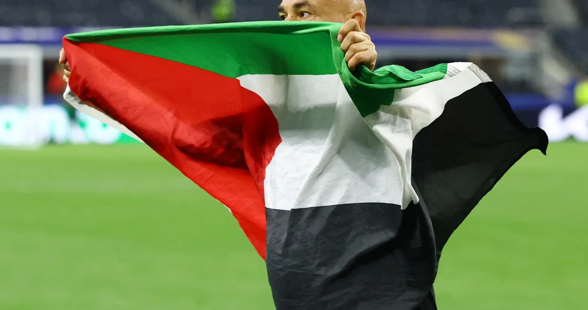 Hombre sosteniendo bandera de Palestina en el campo