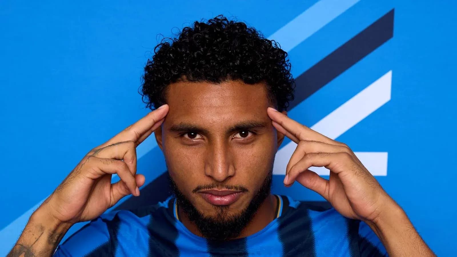 Jugador posando con fondo azul y camiseta de rayas