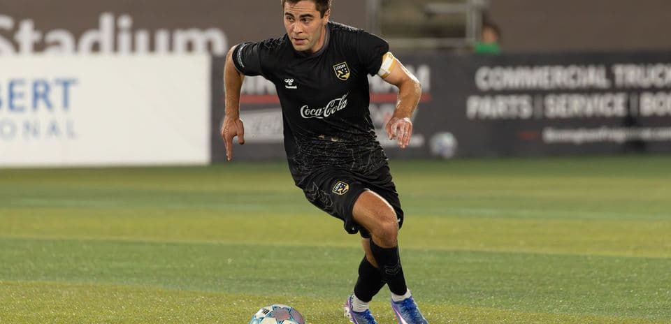 Jugador corriendo con el balón en el campo