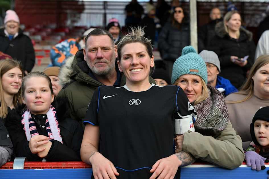 Jugadora de fútbol posando con aficionados sonrientes