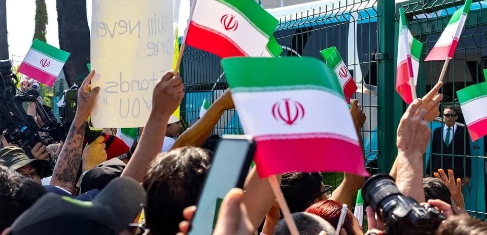Multitud sosteniendo banderas de Irán y carteles