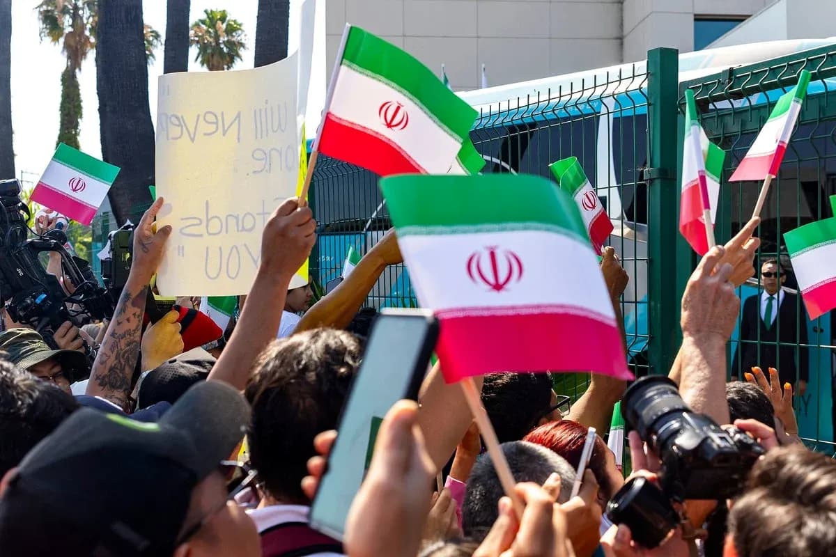 Multitud sosteniendo banderas de Irán y carteles