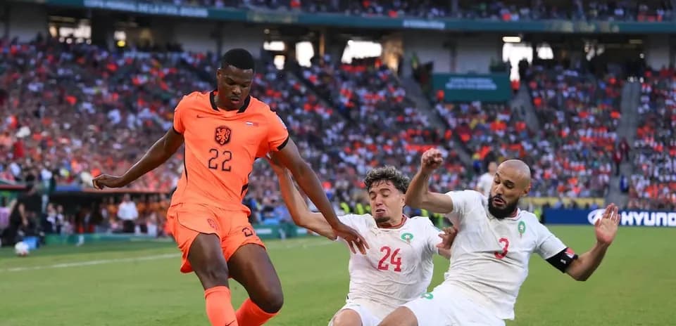 Jugador de Países Bajos driblando entre dos defensores rivales