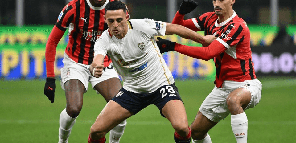 Jugador de Cagliari en acción contra jugadores del AC Milan