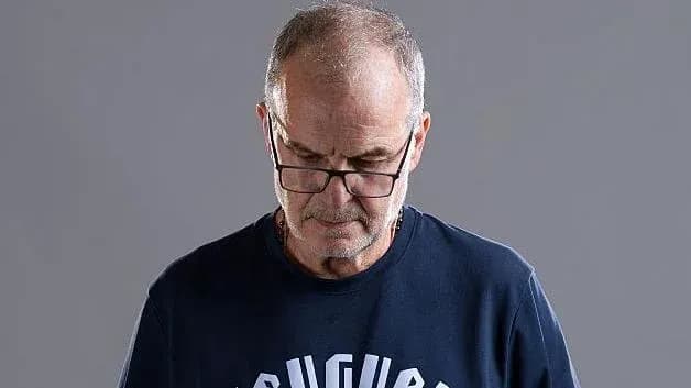 Hombre con gafas mirando hacia abajo, fondo gris