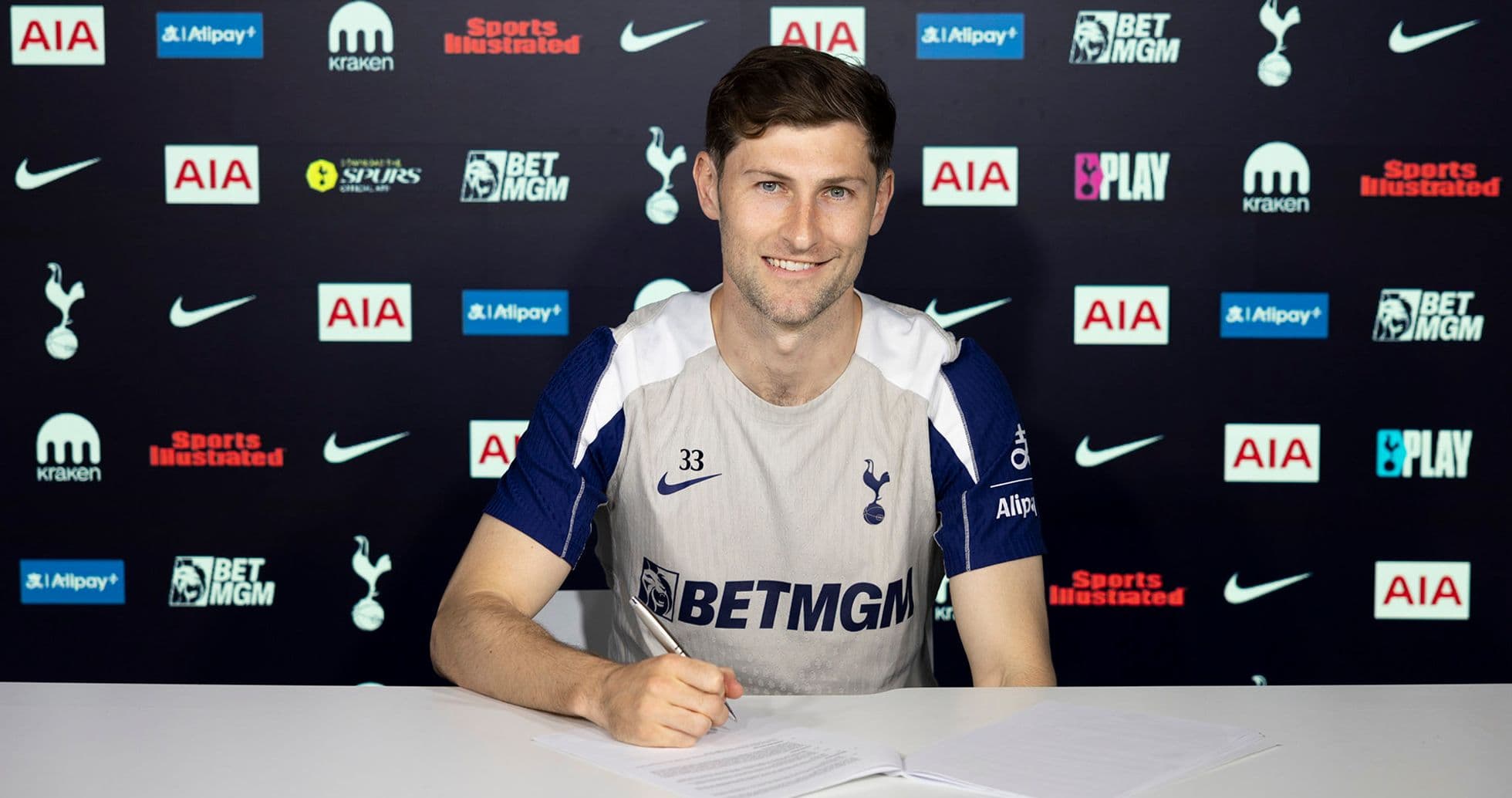 Jugador firmando contrato en mesa de prensa