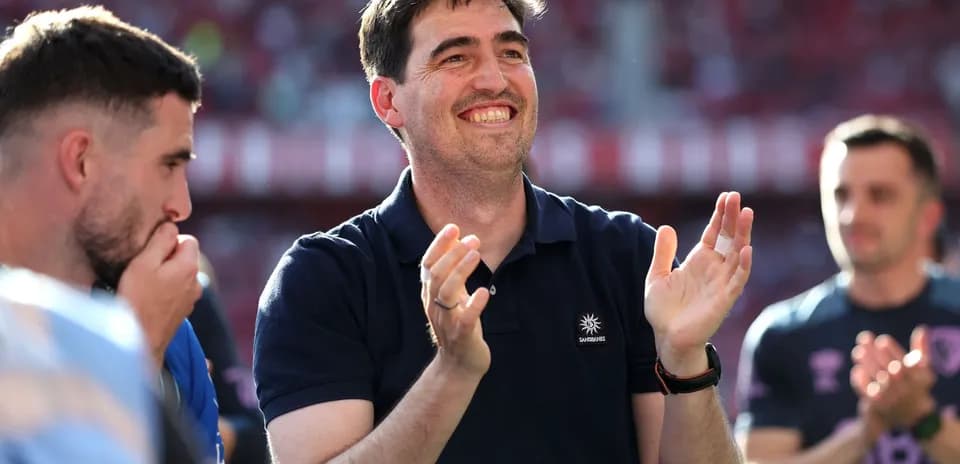 Entrenador aplaudiendo con jugadores en segundo plano