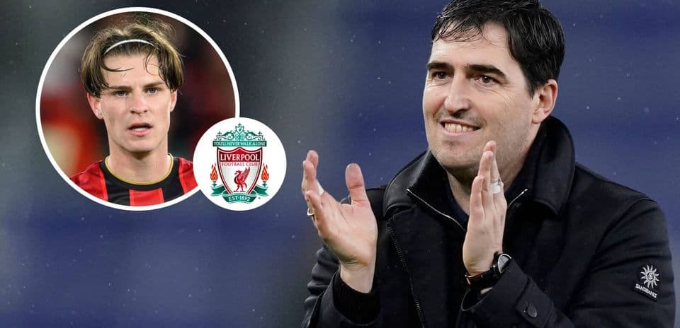 Entrenador aplaudiendo con jugador destacado y escudo de Liverpool