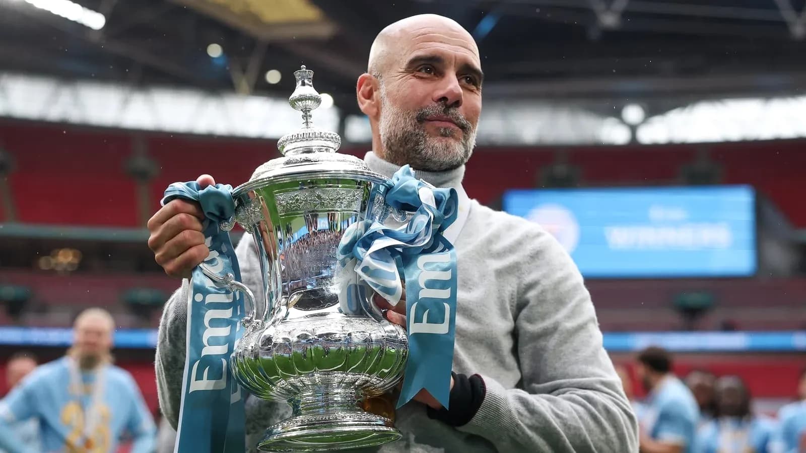 Entrenador sosteniendo el trofeo en el estadio