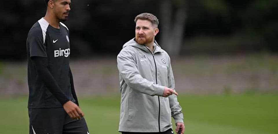 Jugador y entrenador conversando en campo de entrenamiento