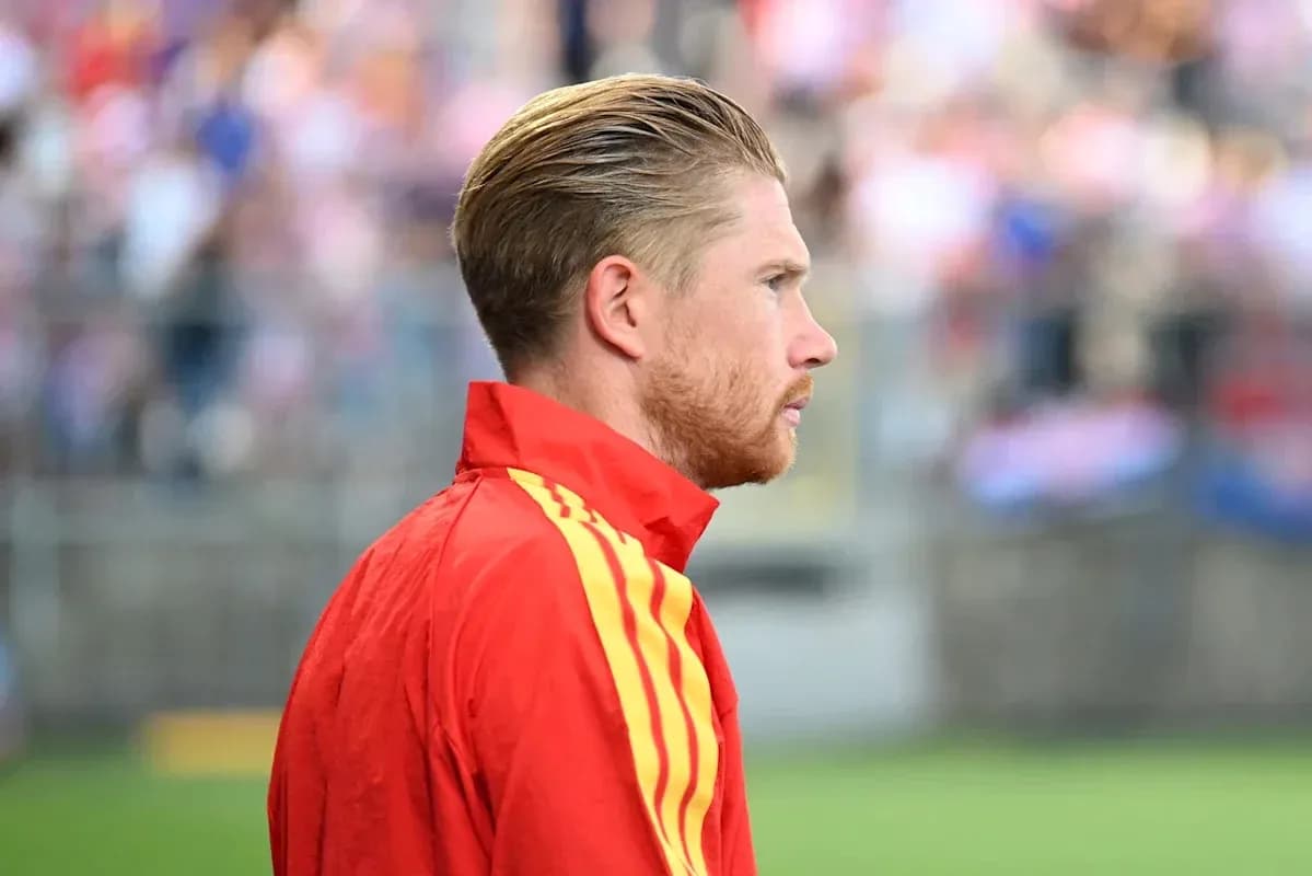 Jugador en chaqueta roja observando el partido