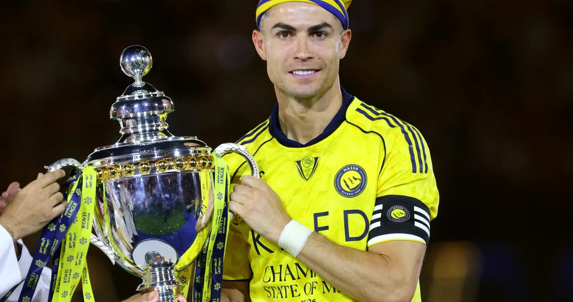 Jugador sosteniendo trofeo con camiseta amarilla Jugador sosteniendo trofeo con camiseta amarilla